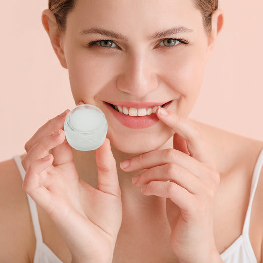 Female holding up Vanilaa lip mask and smiling with finger on the lips