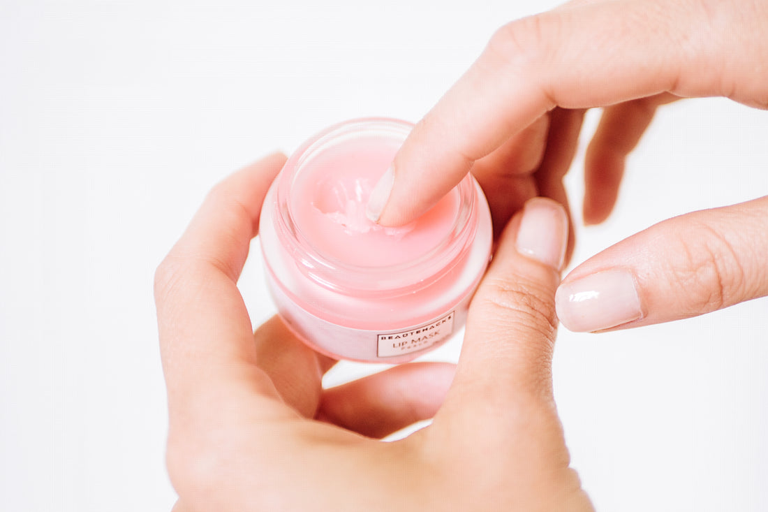 Hands holding Peach lip mask and finger being dipped into the lip mask